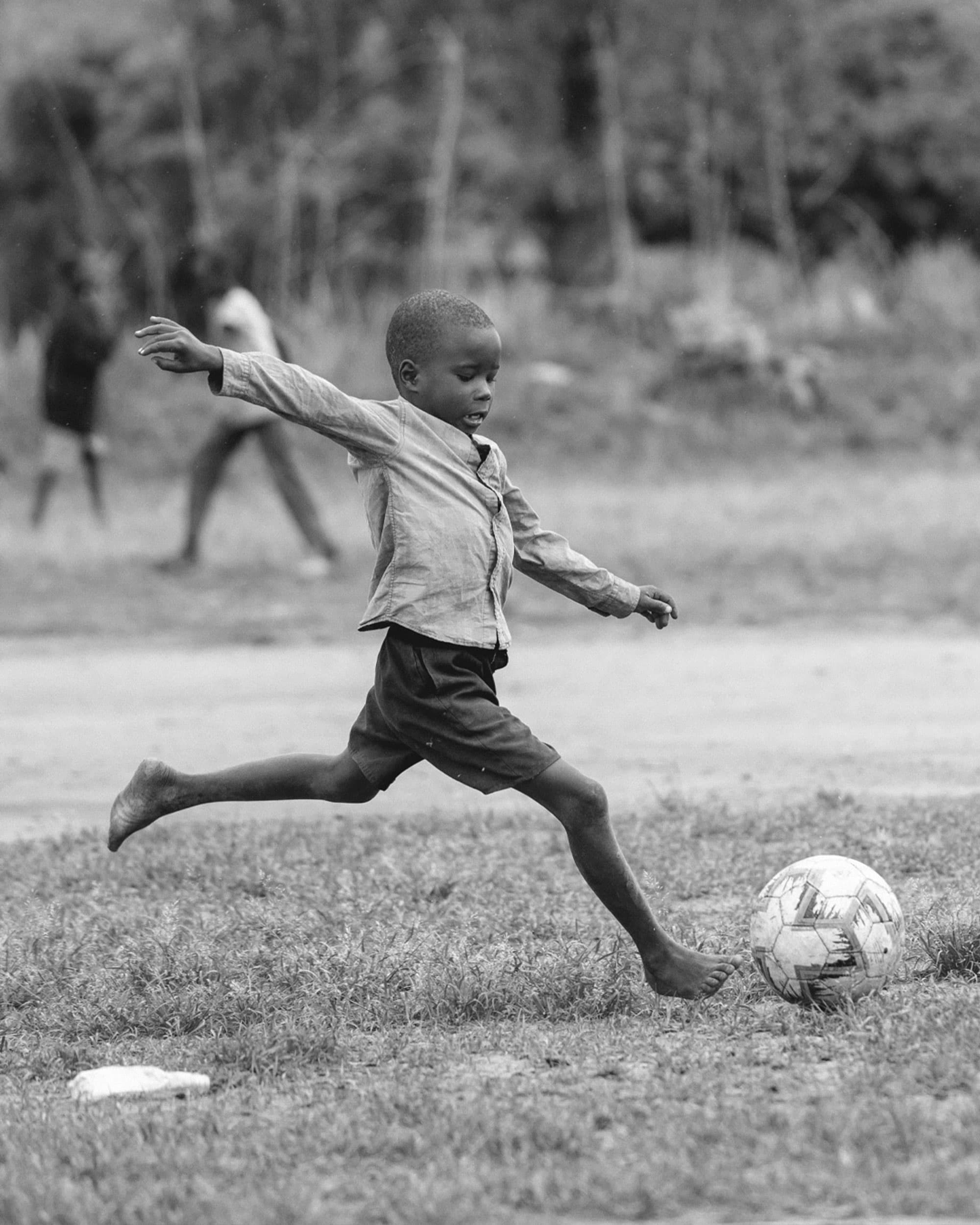 Black and white image of boy playing football